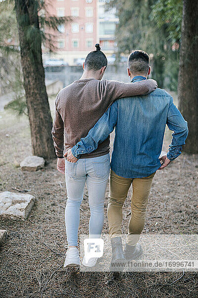 Gay couple walking with arms around at park