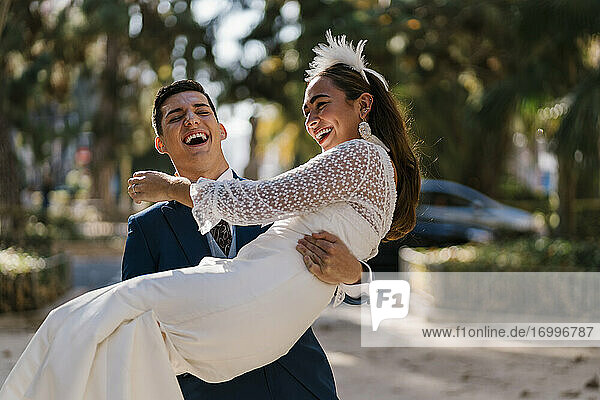 Lachende Braut mit Bräutigam im Park an einem sonnigen Tag