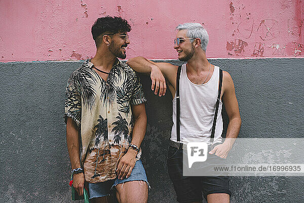 Gay couple in front of pink and grey wall