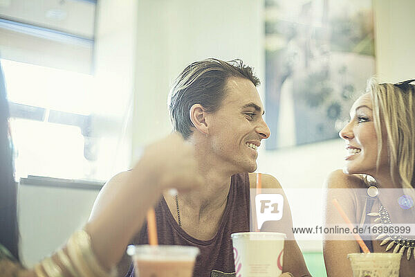 Fröhlicher Mann und Frau schauen sich an  während sie in einem Café Kaffee trinken