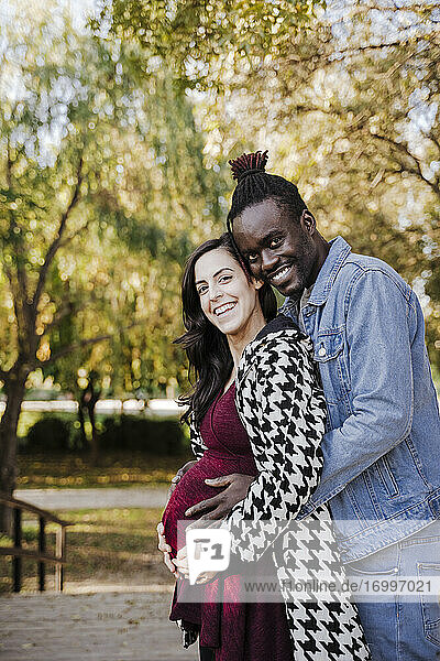 Glückliche schwangere Frau steht mit Mann im Park