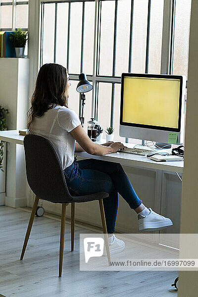 Geschäftsfrau arbeitet am Computer  während sie im Büro sitzt