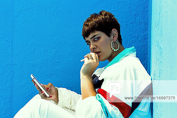 Frau im Swag-Style raucht und überprüft ihr Smartphone