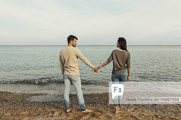 Junge Freundin und Freund halten Hände am Strand