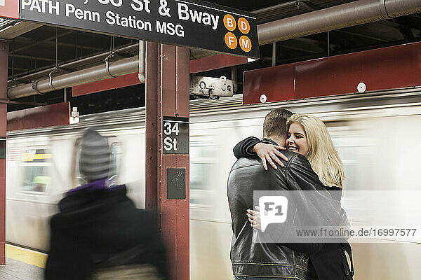 Freundin lächelt  während sie ihren Freund in der U-Bahn-Station umarmt