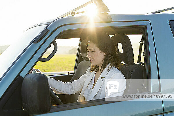 Schöne Frau auf Autoreise mit Auto bei Sonnenuntergang