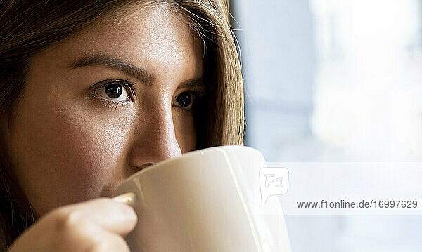 Nahaufnahme einer Frau  die beim Kaffeetrinken im Café wegschaut