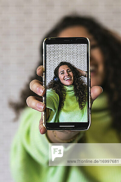 Young woman showing photograph on smart phone