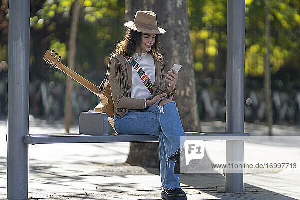 Junge Frau benutzt ihr Smartphone an der Bushaltestelle