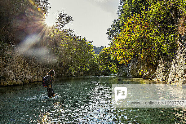 Mann mit Rucksack beim Überqueren des Flusses Acheron in Epirus  Griechenland