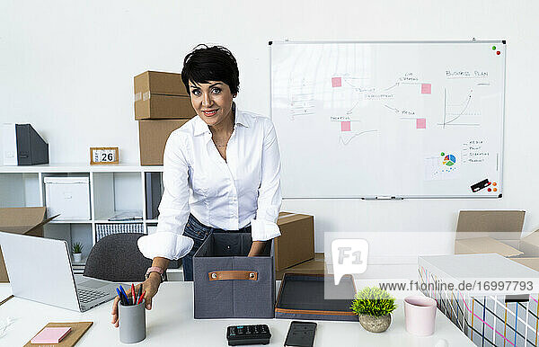 Porträt einer Geschäftsfrau  die ihr Büro vor dem Umzug organisiert