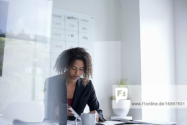 Geschäftsfrau mit Dokument auf dem Schreibtisch sitzend im Büro