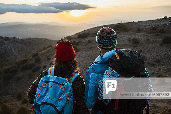 Männliche und weibliche Wanderer genießen im Urlaub den Sonnenuntergang auf einem Berg