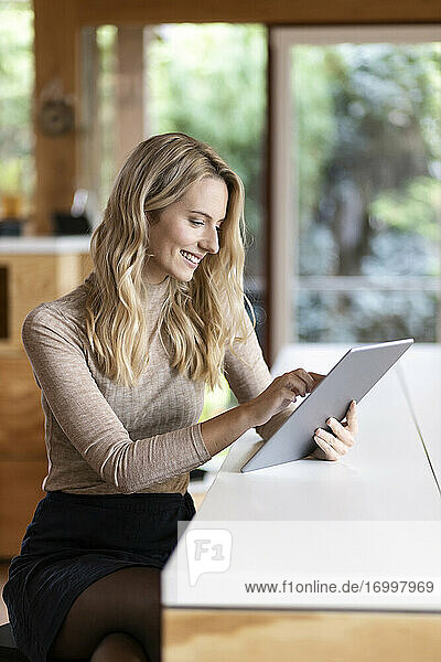 Junge Frau  die zu Hause sitzend an einem digitalen Tablet arbeitet