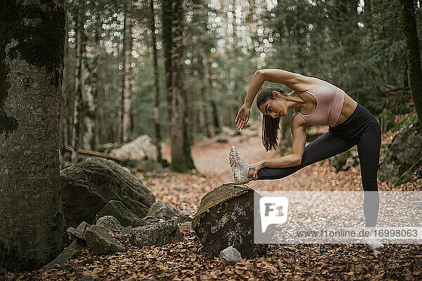Young sportswoman stretching while standing in forest at Ordesa National Park  Huesca  Spain