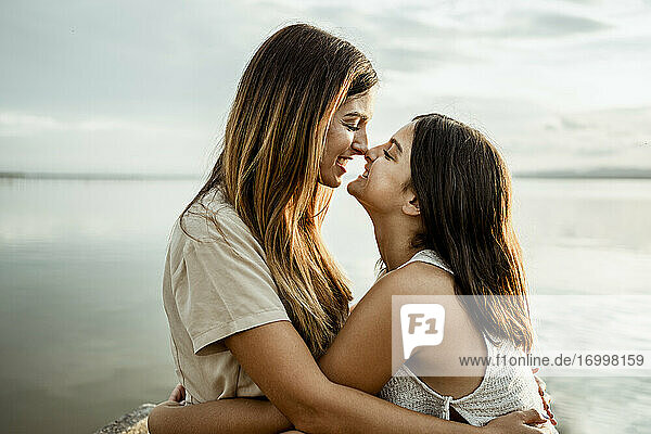 Mutter und Tochter kuscheln Nase am See gegen den Himmel