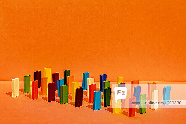 Anordnung von bunten Spielzeugblöcken in einer Reihe auf orangem Hintergrund