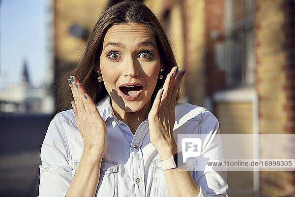 Surprised businesswoman staring with mouth open while standing outdoors