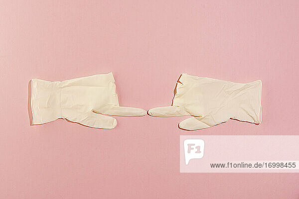 Studioaufnahme eines Paars chirurgischer Handschuhe  die sich mit den Zeigefingern berühren