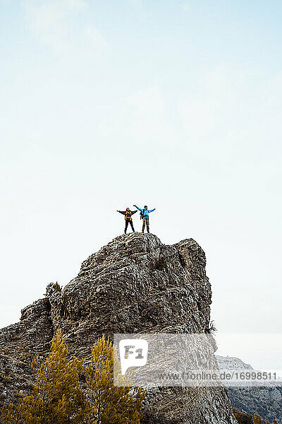 Paar steht auf dem Gipfel eines Felsens gegen den Himmel