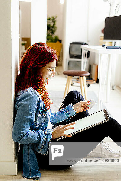 Rothaarige Geschäftsfrau beim Online-Shopping über ein digitales Tablet  während sie im Büro sitzt