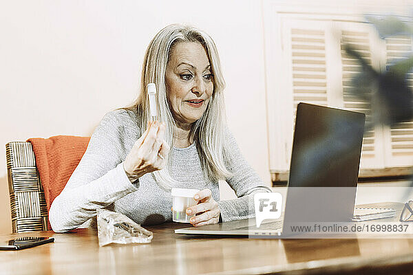 Senior woman discussing about medical sample while taking online consultation at home
