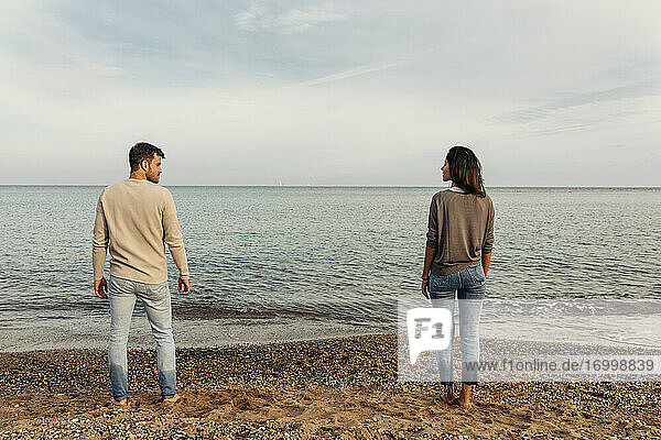 Junges Paar steht auf Sand gegen den Himmel am Strand