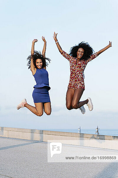 Fröhliche Freundinnen springen auf dem Dach eines Gebäudes