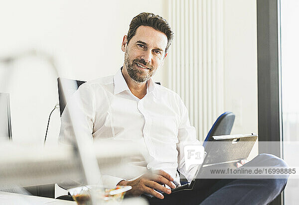 Lächelnder Geschäftsmann mit digitalem Tablet im Büro