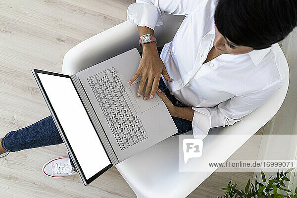 Geschäftsfrau in Bürosessel mit Laptop sitzend