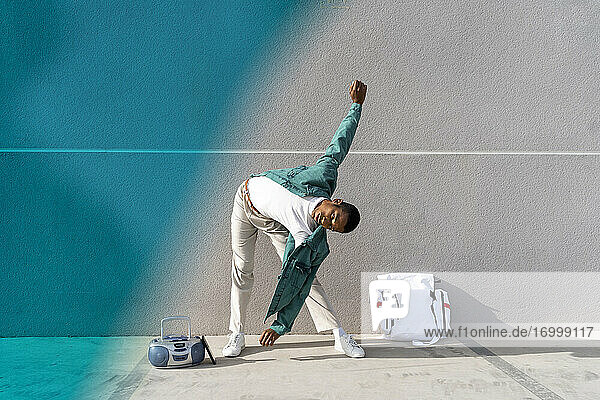 Junger Mann  der vor einer grauen und blauen Wand steht und Sport treibt
