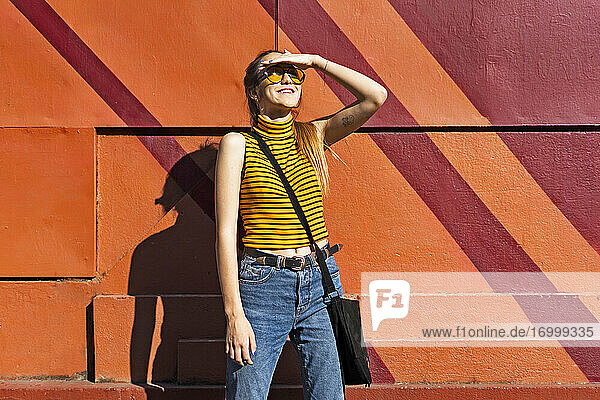Teenager-Mädchen an einer Mauer  das den Sonnenschein genießt