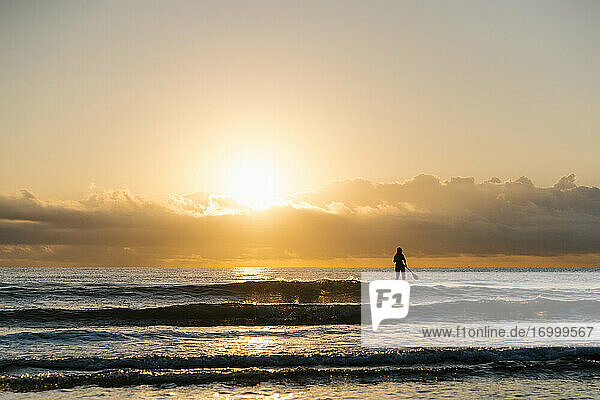 Silhouette woman paddleboarding on Mediterranean Sea at dawn