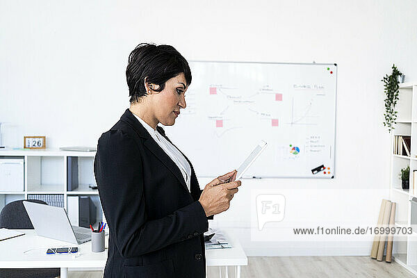 Porträt einer Geschäftsfrau im Büro stehend mit digitalem Tablet in den Händen