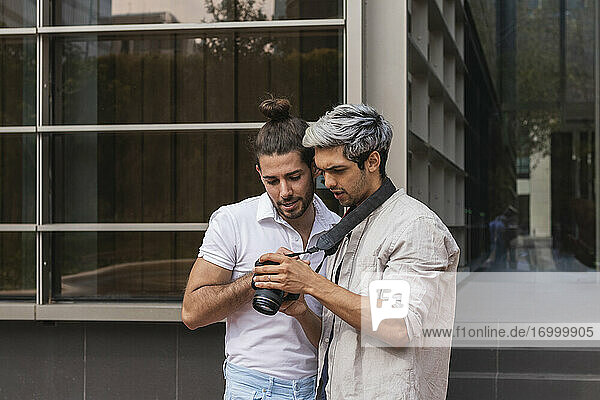 Man and gay partner looking at camera in city