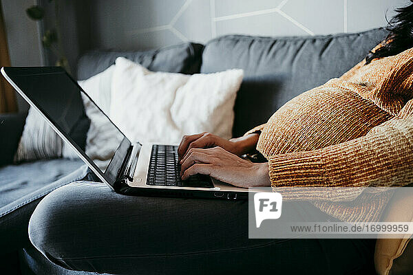Schwangere Frau benutzt Laptop zu Hause