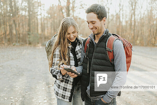 Young couple using smart phone during autumn hike