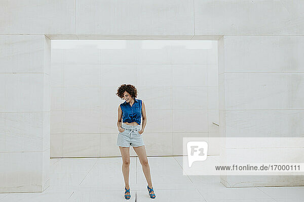 Smiling woman with curly hair standing against tiled wall