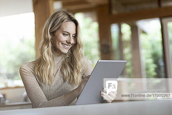 Junge Frau benutzt ein digitales Tablet  während sie zu Hause sitzt