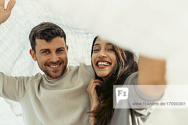 Lächelnde Freundin und Freund verbringen ihre Freizeit unter dem Schal