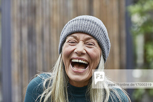 Laughing mature woman against house