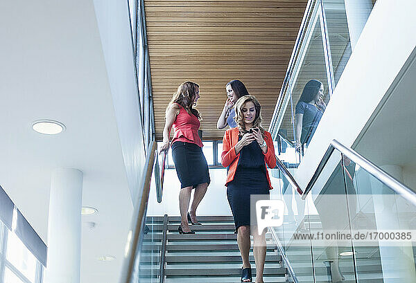Female coworkers moving down steps in office