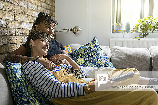 Lesbisches Paar lächelt beim Fernsehen auf dem Sofa zu Hause