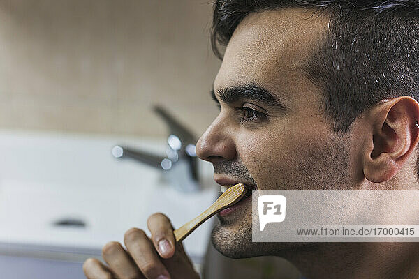 Young man brushing teeth with bamboo toothbrush