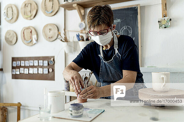 Künstlerin bei der Arbeit in der Keramikwerkstatt während der COVID-19
