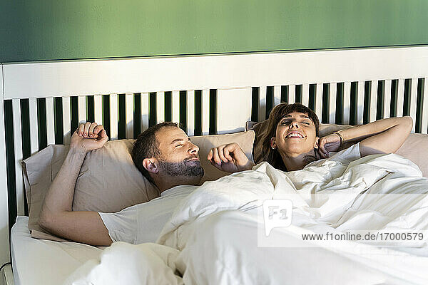 Mann und Frau wachen langsam auf  während sie zu Hause im Bett liegen