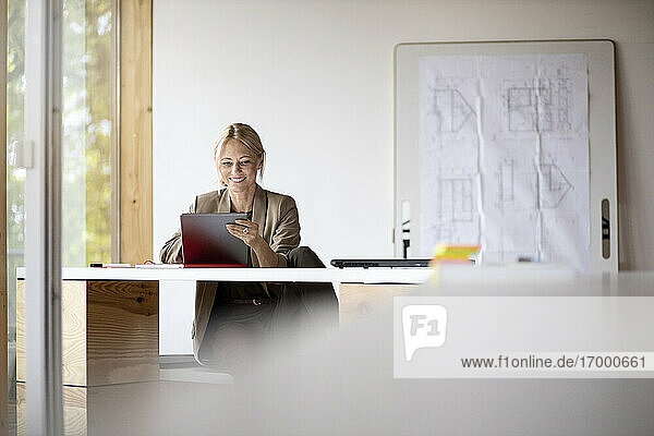 Geschäftsfrau lächelnd bei der Arbeit an einem digitalen Tablet zu Hause