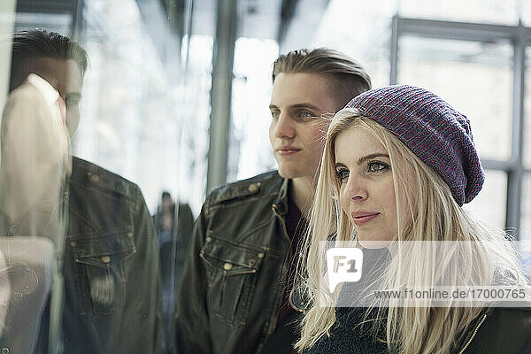 Girlfriend wearing knit hat doing window shopping while standing with boyfriend by store window