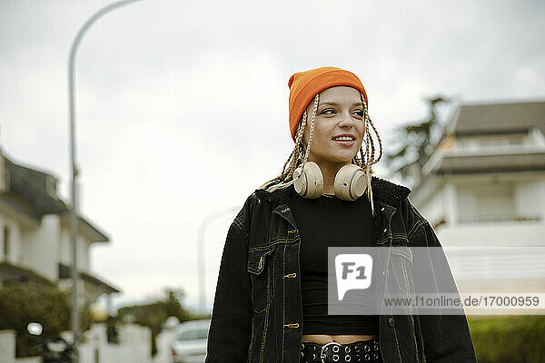 Lächelnde junge Frau mit Kopfhörern  die in den Himmel schaut