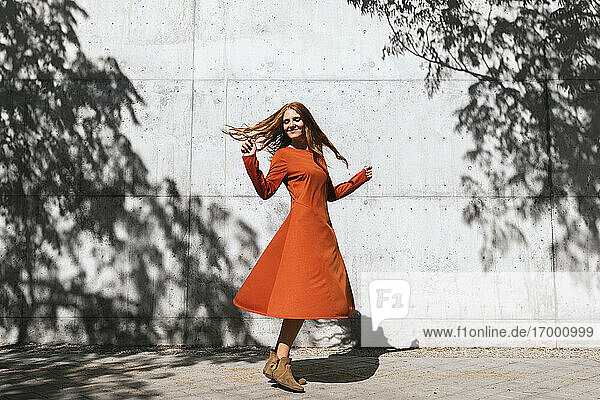 Glückliche Frau tanzt gegen Baum Schatten Wand